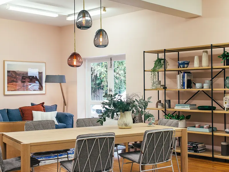 Salon lumineux d'un appartement, avec une table à manger et des étagères.